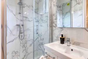 a white bathroom with a sink and a shower at The New White Appart'Hôtel Vitry - Next to Paris in Vitry-sur-Seine