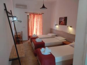a hotel room with three beds and a lamp at Kalypso studio Resorts in Kavos
