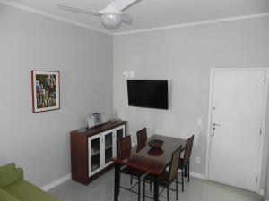 a dining room with a table and a tv on a wall at Apartamento Djalma Ulrich 1 in Rio de Janeiro