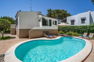 a swimming pool in front of a house at Villa Gloria in Cala'n Bosch