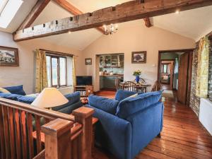 a living room with blue couches and wooden floors at Hollins Farm Barn in Natland