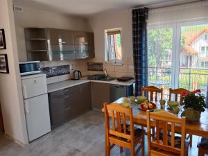 a kitchen with a table and chairs and a dining room at Apartamenty Obok Ruin in Trzęsacz