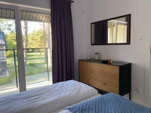 een slaapkamer met een bed, een spiegel en een raam bij Domek Pod Sosnami in Rozewie