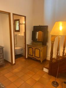 une salle de bains avec une télévision sur un support à côté d'une lampe dans l'établissement Le Mazet de choubouloute, à Saint-Gilles