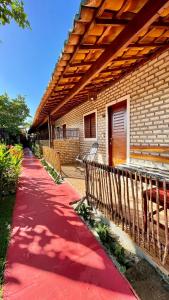 a brick house with a red sidewalk next to a building at Pousada Brasil - São Miguel do Gostoso in São Miguel do Gostoso