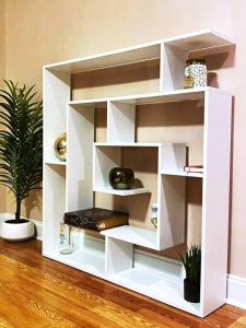 a white book shelf in a room with a plant at 3 Story Lake House Near Historic Downtown in Charleston