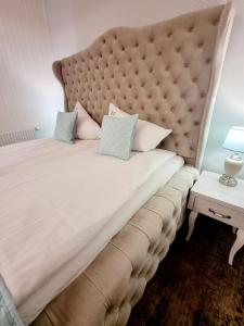 a large bed with a large headboard and a table at Villa Justyna in Pobierowo