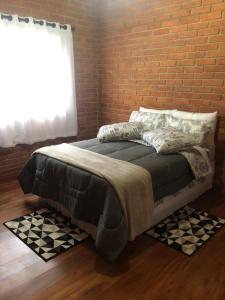 a bed in a room with a brick wall at Casa de Campo Meu Pequeno Paraíso in Gonçalves