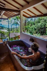 eine Frau, die in einer Badewanne vor einem Fenster sitzt in der Unterkunft Selva Armonia Immersive Jungle Resort in Uvita