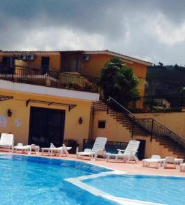 a swimming pool with lounge chairs and a building at Marasusa villaggio in Parghelia