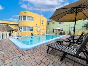 a swimming pool with a bench and an umbrella at Silver Spray Motel in Hollywood