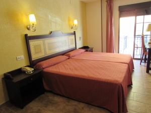 a hotel room with a bed with a orange bedspread at PARAISO PLAYA Hotel in Isla Cristina +37 photos