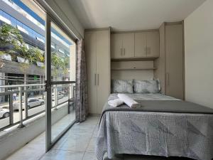um quarto com uma cama e uma grande janela em MA01- Kitnet com Ar | Vista Big Wheel | Garagem em Balneário Camboriú