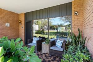 eine Terrasse mit Korbmöbeln und Pflanzen in der Unterkunft Fi's Beach House in Port Macquarie