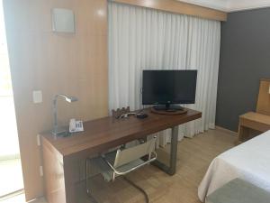 Lindo Flat na Barra da Tijuca com vista para o mar في ريو دي جانيرو: غرفة نوم بها مكتب وبه شاشة كمبيوتر