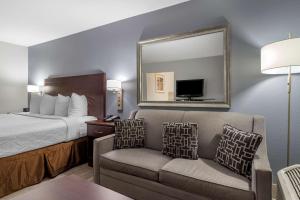 ein Hotelzimmer mit einem Bett, einem Spiegel und einem Stuhl in der Unterkunft Best Western Plus Orange County in Vidor