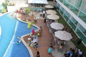a group of people sitting around a pool with umbrellas at Paradiso Peró Praia Hotel in Cabo Frio