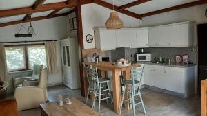 a kitchen with white cabinets and a bar with stools at Bungalow de Pluumpot in Scherpenisse