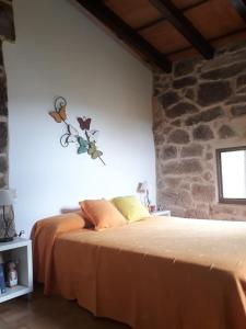 1 dormitorio con cama y pared de piedra en Casa de pueblo en San Estevo Ribas de Sil, en Ourense