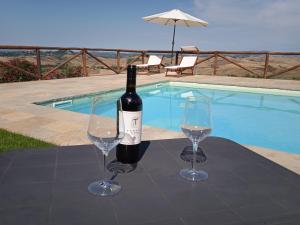 基昂尼的住宿－LA CASA DI CHIANNI La Pieve 2，游泳池附近的桌子上放着一瓶葡萄酒和两杯酒