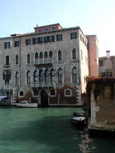 ein großes Backsteingebäude mit einem Boot im Wasser in der Unterkunft At Home a Palazzo in Venedig