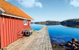 un bâtiment rouge situé sur un quai à côté d'une masse d'eau dans l'établissement Amazing Home In Henn With House Sea View, à Henån