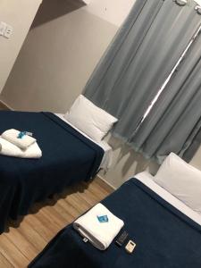 Ágape Hotel في ريو فيرد: سريرين في غرفة ذات أغطية زرقاء ووسائد بيضاء