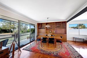 a dining room with a table and chairs and large windows at Fi's relaxing Beach House in Port Macquarie