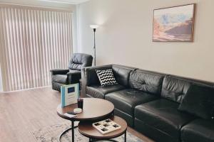 a living room with a black leather couch and a table at Spacious 2-bedroom apartment in Camrose