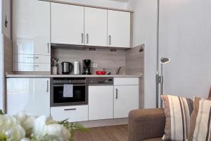 uma cozinha com armários brancos e um fogão em Ferienwohnung-47-mit-Schwimmbad-Sauna-Residenz-Passat-Doese em Cuxhaven