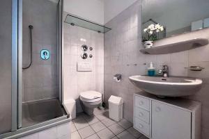 uma casa de banho com um lavatório, um chuveiro e um WC. em Ferienwohnung-47-mit-Schwimmbad-Sauna-Residenz-Passat-Doese em Cuxhaven