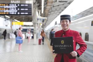 東京にあるShangri-La Tokyoの駅看板を持つ制服の男