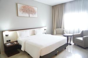 a hotel room with a large bed and a chair at Rylich Panorama Hotel in Sorong