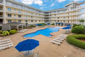 una vista exterior de un hotel con piscina, sillas y sombrillas en The Sandbridge Dunes - Katz Meow 204, en Virginia Beach