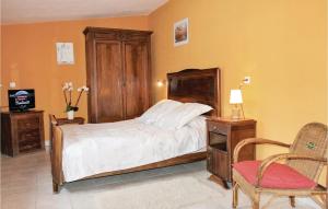 a bedroom with a bed with a wooden headboard and a chair at Cozy Home In Montsegur Sur Lauzon in Montségur-sur-Lauzon