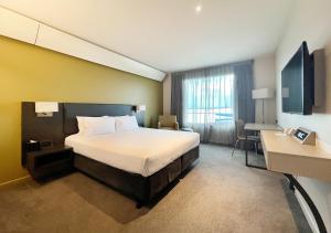 a hotel room with a bed and a desk at Sudima Auckland Airport in Auckland