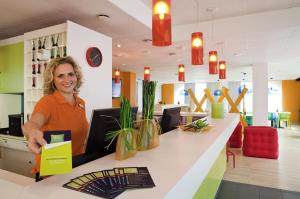 a woman sitting at a counter in a store at ibis Styles Duesseldorf-Neuss in Neuss