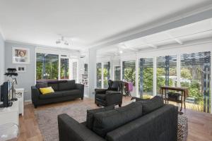 a living room with a couch and chairs and windows at Cosy Corner - BYO Linen in Torquay