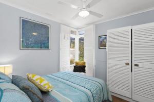 a white bedroom with a bed and a window at Cosy Corner - BYO Linen in Torquay