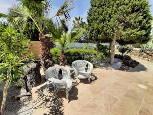 two white chairs sitting on a patio with palm trees at VILLA RASOA chambre LIBELLULE in Cap d'Agde