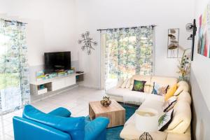 a living room with two couches and a tv at Villa L'Artist en bord de mer avec piscine privée in Sainte-Rose