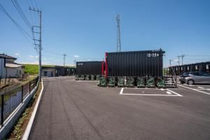 a parking lot with two shipping containers and a car at HOTEL R9 The Yard Honjo in Honjo