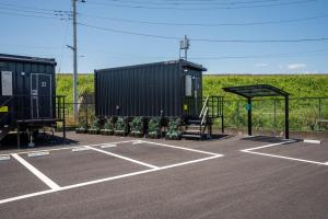 a parking lot with two shipping containers and a bench at HOTEL R9 The Yard Honjo in Honjo