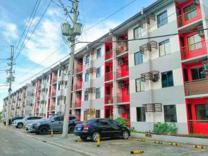 ein großes Apartmenthaus mit Autos auf einem Parkplatz in der Unterkunft Nordic Themed 1BR Condo - 50 mbps net - Marilao Bulacan - TheRichPlacePh in Marilao