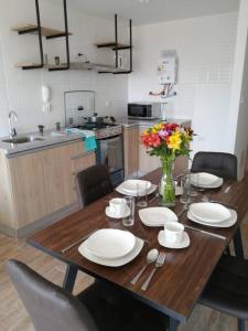 a wooden table with plates and flowers on it in a kitchen at MODERNO LOFT BARRANCO, VISTA PANORAMICA in Lima