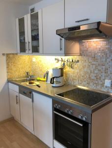 a kitchen with white cabinets and a black stove top oven at Steinwarder 1 - Haus "Seerose" ST1 055 Steinwarder 1 in Heiligenhafen +8 photos