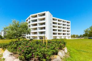 a white apartment building with flowers in a garden at Steinwarder 1 - Haus "Seerose" ST1 055 Steinwarder 1 in Heiligenhafen