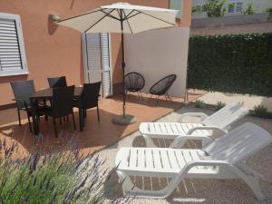 um pátio com uma mesa, cadeiras e um guarda-sol em Tomena apartments em Trogir