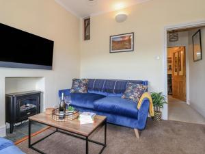 a living room with a blue couch and a fireplace at Primrose Cottage in Ambleside