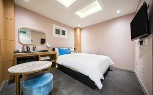 een slaapkamer met een bed, een tafel en een spiegel bij Bay 202 Hotel in Busan